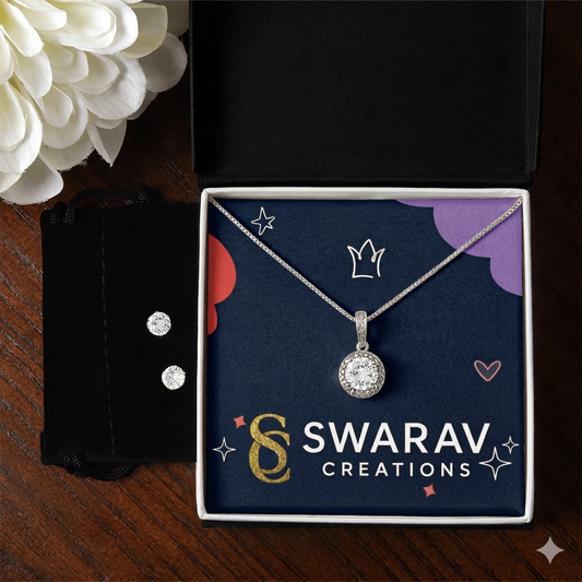 Silver necklace with pendant in a 'Swarav Creations' box on a wooden surface with flowers.