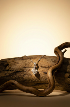 Alluring Beauty diamond pendant necklace displayed on natural driftwood with a warm background