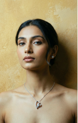 Woman wearing a forever love necklace with a heart-shaped pendant and earring against a beige background