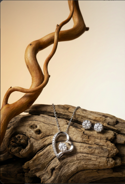Silver jewelry set including a heart-shaped pendant and earrings on a wooden surface.
